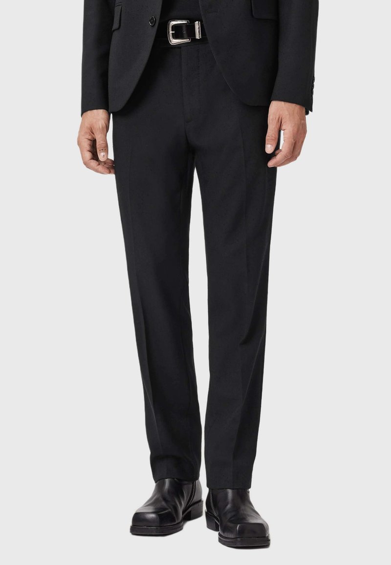 Pantaloni neri su misura con vestibilità dritta, realizzati in un tessuto liscio, con frontale piatto e abbinati a stivaletti neri in pelle.