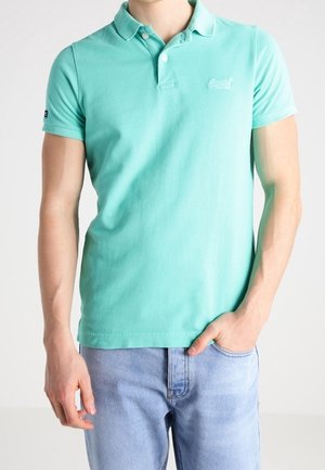 Polo en vert menthe en coton doux, doté d'une patte de boutonnage à deux boutons, d'un petit logo sur la poitrine gauche et de manches courtes.