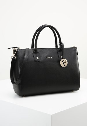 Sac à main en cuir noir avec un design structuré, deux poignées supérieures, une bandoulière amovible et une étiquette en métal argenté. Texture lisse avec des accents minimalistes.