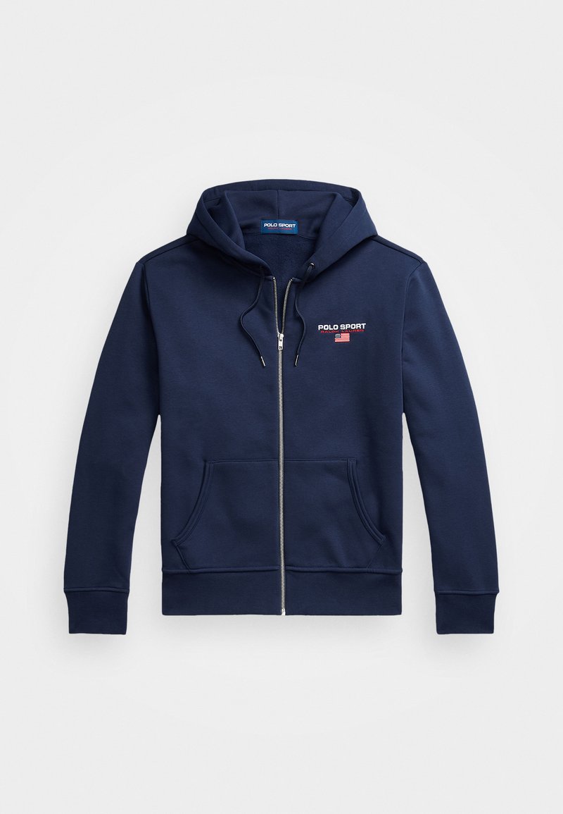 Marineblå zip-pullover laget av mykt stoff, med hette, frontlommer og et logo-patch med røde og blå aksenter.