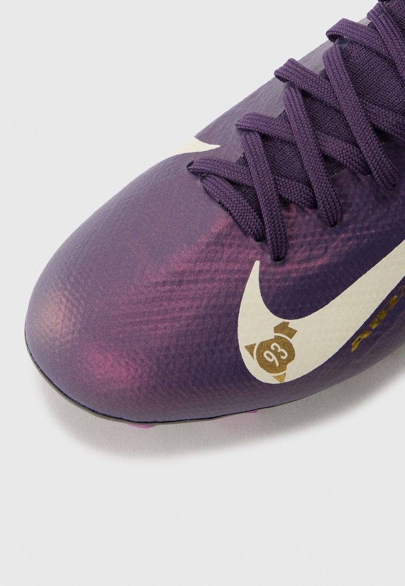 Botas de fútbol Nike en degradado púrpura con una superficie texturada. Presenta una suela negra, cordones a juego y un logo Swoosh blanco con detalles en dorado.