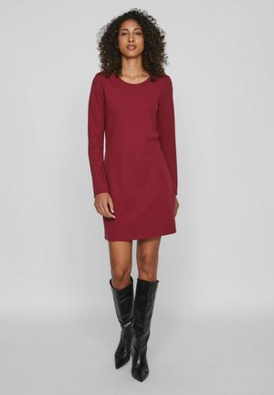 Vestido burdeos de manga larga con escote redondeado, hecho de tela suave, combinado con botas de cuero negro hasta la rodilla.