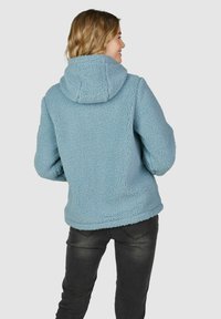Veste en polaire bleu clair avec capuche, dotée d'une texture douce et d'une coupe décontractée. La veste a des manches longues et un ourlet court.