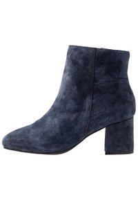 Botines de ante azul marino con tacón cuadrado, puntera afilada y diseño sin costuras. Superficie texturizada sin cierres visibles ni adornos.