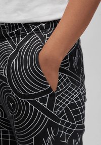 Zwarte sweatpants van een katoenmix, met een geometrisch wit patroon, zijzak, elastische tailleband en een gladde textuur.