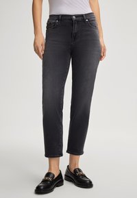 Jean en denim noir avec une coupe droite, texture subtile, design à cinq poches et une fermeture éclair avec un bouton.