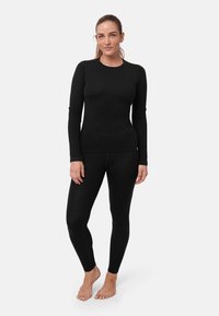 Top térmico negro y leggings hechos de una tela suave y elástica. Presentan mangas largas y un diseño ajustado con costuras planas.