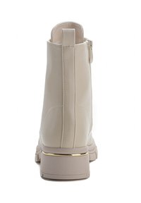 Stivaletto beige con superficie in pelle liscia, punta tonda e un accento dorato attorno alla suola. Presenta un tassello sul retro e una cerniera laterale.