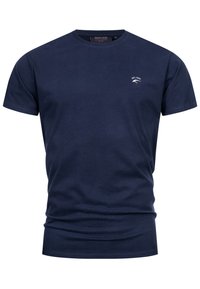 Camiseta de algodón azul marino con mangas cortas, cuello redondo y un pequeño logo blanco en el pecho. Textura suave y diseño ajustado.