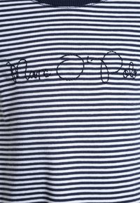 Granatowa i biała koszulka z bawełny w paski z haftem, na którym widnieje napis "Marc O'Polo" na wysokości klatki piersiowej.