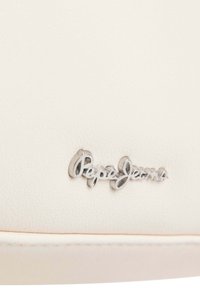 Pepe Jeans branded tag embossed on a smooth, light cream synthetic leather background, featuring a subtle textured finish.