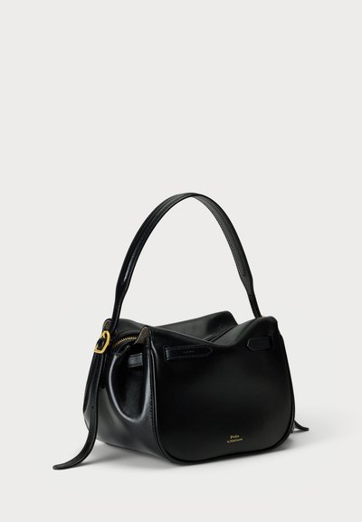 Bolsa de couro preta com forma arredondada, textura lisa, alça curta e detalhes em metal dourado. Apresenta um fecho de zíper e detalhe com logotipo.