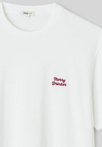 T-shirt en coton blanc à col rond, avec un texte brodé rouge "Merry Drinker" sur la partie gauche de la poitrine.
