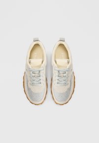 Spordijalatsid, mille pealmine osa on kreemika värvusega, hõbedaste detailide ja perforatsioonidega. Omavad tekstureeritud helepruuni kummist talda ja sobivaid paelu.