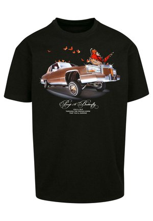 Fekete póló, amelyen egy barna klasszikus autó grafika látható pillangó motívumokkal, élénk színekkel, és stilizált szöveggel a kép alatt.