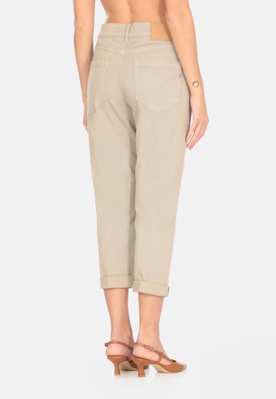 Pantaloni cropped beige con cuffs arrotolati, due tasche posteriori e un'etichetta in pelle in vita. Abbinati a sandali con tacco color sabbia.