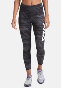 Leggings neri a vita alta con motivi testurizzati e dettagli del logo bianco. Abbinati a scarpe da ginnastica grigie con accenti viola.