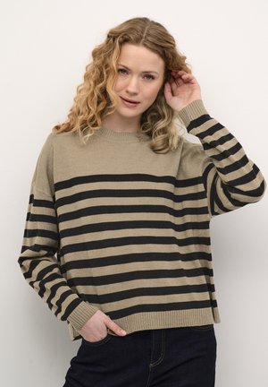 Triibuline beige ja must kampsun. Valmistatud pehmest kudumist, omades pikki varrukaid, ümarat kaelust ja vabamat lõike, millel on soonikkoes mansetid ja alläär.