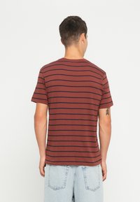 Bordeaux gestreepte t-shirt met navy horizontale lijnen, korte mouwen, ronde hals en een relaxte pasvorm. Gemaakt van zachte stof.