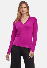 Fuchsia V-hals trui met lange mouwen, gemaakt van lichtgewicht gebreid materiaal, gladde textuur en een ontspannen pasvorm, gecombineerd met zwarte broek.