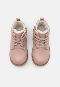 Stivaletti alla caviglia in pelle rosa con lacci texturizzati e fodera in pelliccia sintetica, dotati di suola in gomma marrone e tacco piccolo. Cerniera laterale per una vestibilità facile.