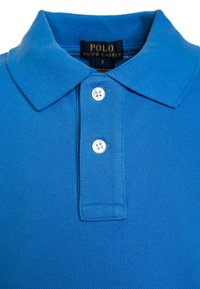 Camisa polo azul hecha de material texturizado, con un cuello clásico, dos botones blancos y una etiqueta que dice "POLO RALPH LAUREN."