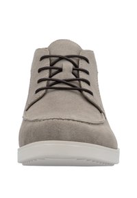 Scarpa in suede grigia con una forma bassa, punta rotonda, lacci marroni e suola in gomma bianca. Superficie texture e dettagli di cucitura minimi.