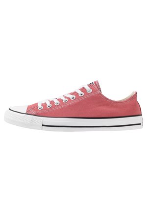 Zapatilla baja de lona rosa con suela de goma blanca, cordones blancos, ojales metálicos y rayas negras alrededor de la suela.