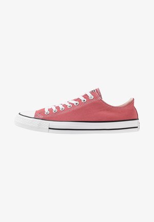 Zapatilla baja de lona rosa con suela de goma blanca, cordones blancos, ojales metálicos y rayas negras alrededor de la suela.