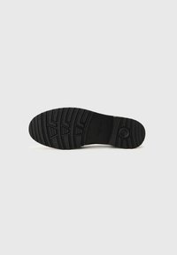 Black rubber shoe sole with a textured, patterned grip; features a round logo and a clean, simple design with no visible wear.