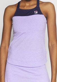 Ljuslila träningslinne med en mörklila halsringning, med en liten logotyp på vänster sida och en figursydd design med slät textur.