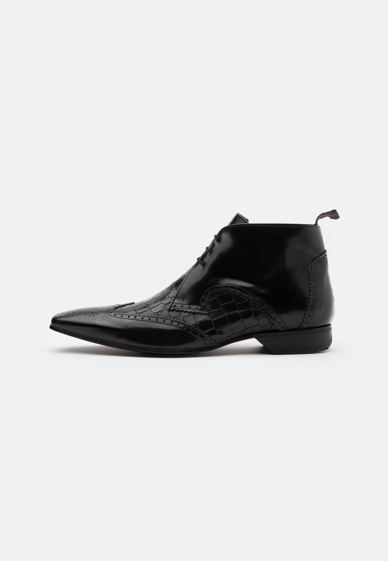 Botas de tobillo de cuero negro con punta afilada, con acentos de textura de cocodrilo y detalles de brogue decorativos. Cintas delgadas y lengüeta de agarre.