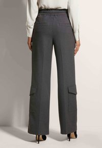 Graue weit geschnittene Hose mit elastischem Bund, zwei Gesäßtaschen und Cargo-Taschen an den Seiten. Verfügt über eine glatte Textur und ein maßgeschneidertes Design.