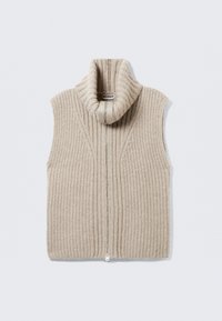Beige gestrickte ärmellose Weste mit hohem Kragen, vertikaler Rippstruktur und einem Reißverschluss auf der Vorderseite. Etikett im Kragen sichtbar.