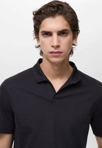 Marinblå pikétröja med texturerad tyg, tvåknappsknäppning och korta ärmar. Enkelt design utan mönster eller detaljer.