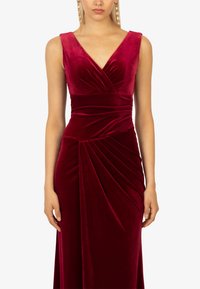 Samtburgunder Kleid mit V-Ausschnitt, ärmellosem Design und gefälteltem Detail an der Taille für Textur und Drapierung.