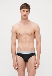 Schwarze Unterhosen mit einem grauen elastischen Bund, der "Calvin Klein" in Hellblau zeigt. Glattes Material, körpernahe Passform und minimale Markenkennzeichnung.
