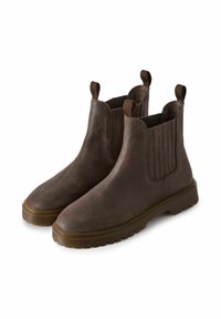 Botas de cuero marrón hasta el tobillo con paneles laterales elásticos y tiradores, que cuentan con una suela gruesa y texturizada para agarre y estabilidad.
