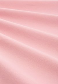 Ljust rosa tyg med en strukturerad väv, som visar släta, vikta ytor och en mjuk, matt finish.