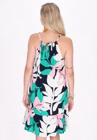 Rochie fără mâneci cu un spate pliat, model colorat cu frunze în roz, verde și alb pe un fundal bleumarin, cu o margine volanată.
