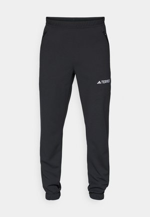 Pantalons de sport noirs en tissu doux ; dotés d'une taille élastique, de jambes fuselées et de poches latérales zippées. Logo "TERREX" imprimé en blanc.