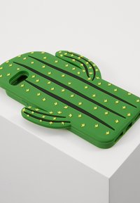 Coque de téléphone en forme de cactus verte en silicone doux avec des accents jaunes. Présente une surface texturée et des découpes pour l'appareil photo et les boutons.