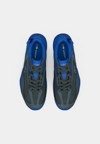 Αθλητικά παπούτσια Lacoste με γκρι και μπλε χρώματα. Διαθέτουν δίχτυ και συνθετικό υλικό, υφή στην επιφάνεια και κορδόνια για υποστήριξη.