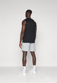 Black sleeveless t-shirt, gray shorts, white sneakers, and socks. Focus on athletic fit and smooth fabric texture. Minimalist design.
