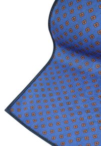 Niebieska tkanina w wzory z geometrycznym wzorem, w którym znajdują się małe pomarańczowe kwadraty. Krawędzie wykończone są ciemnym szwem dla zwiększenia trwałości.