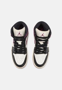 Paire de baskets montantes Air Jordan noires, blanches et roses avec des lacets noirs et le logo Jumpman sur la languette, vue de dessus.