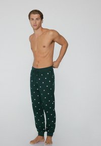 Groene pyjamabroek met een trekkoord in de taille; heeft kleine ronde patronen overal; zachte stof met een relaxte pasvorm.