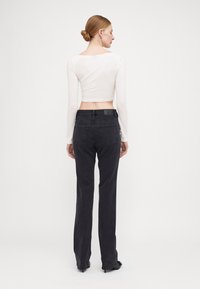 Black straight-leg jeans with a high waist and four pockets, paired with a fitted, long-sleeve white crop top. Matte finish, smooth texture.