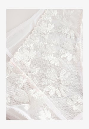 Hieno valkoinen pitsikangas, jossa on herkkiä kukkaommeluja, pehmeä tekstuuri ja hienovaraiset läpinäkyvät design-elementit.