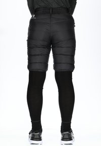 Black insulated shorts with a quilted design and elastic waistband, worn over black leggings, paired with black athletic shoes.
